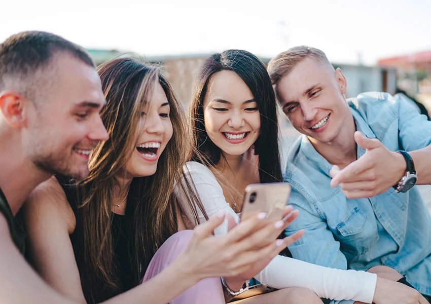 Eine junge Gruppe von Freunden planen begeistert und freudig eine gemeinsame Typisierungs-Aktion am Handy.